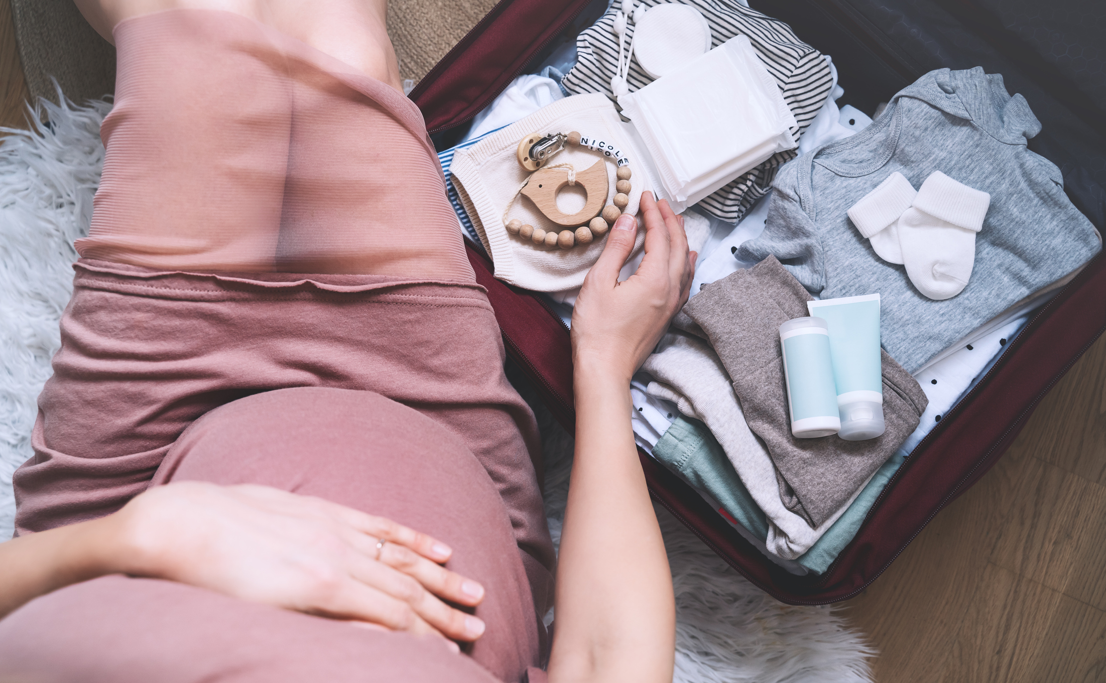 Pregnant woman hugging belly and packing maternity hospital bag