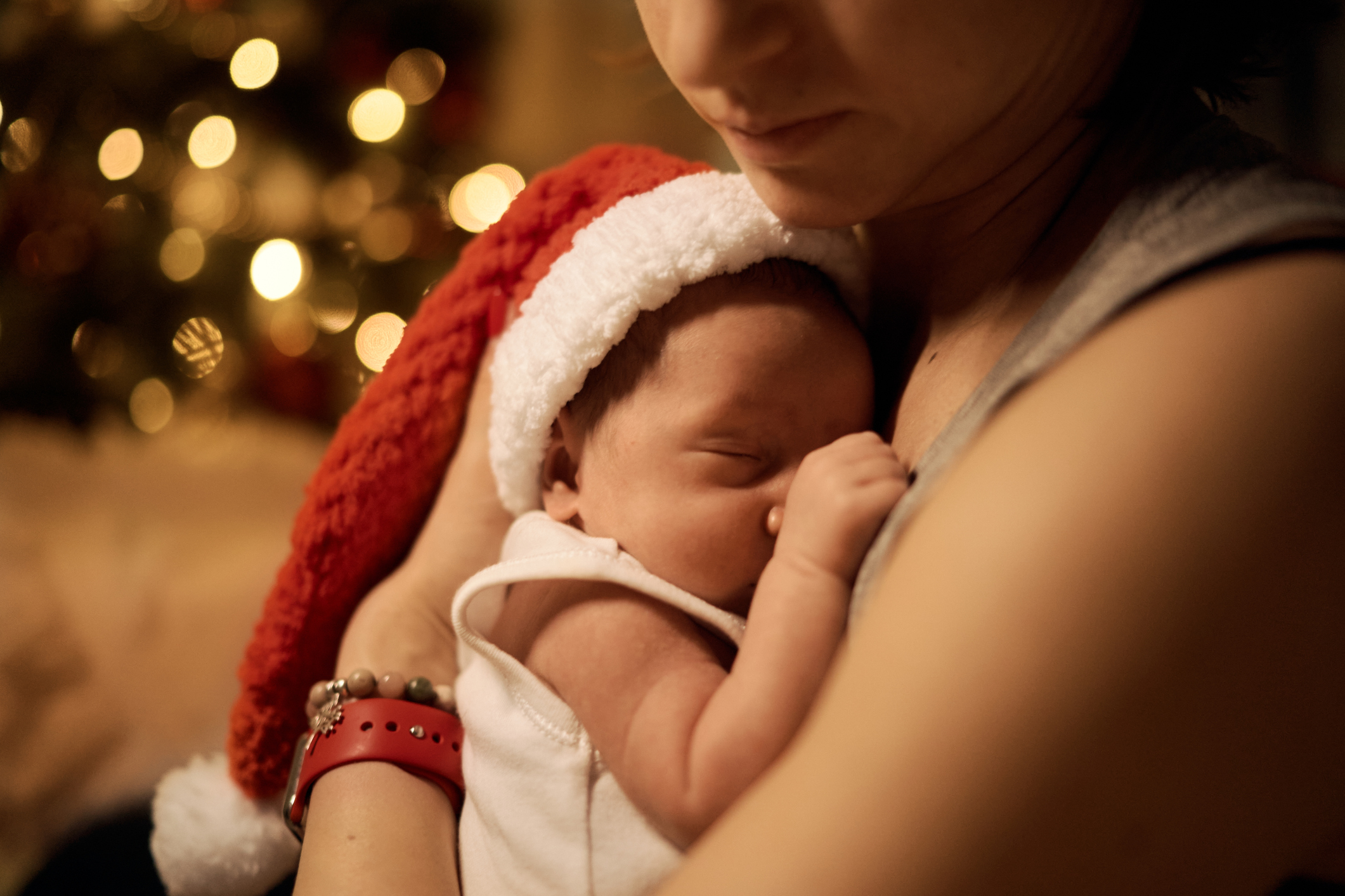 Happy young mother posing with newborn son under Christmas tree