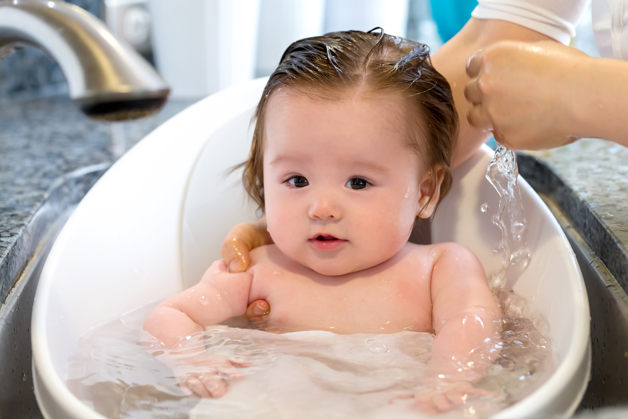 A baby takes a bath in a little tub