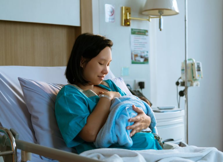 A new mom breastfeeds her baby in the hospital after giving birth