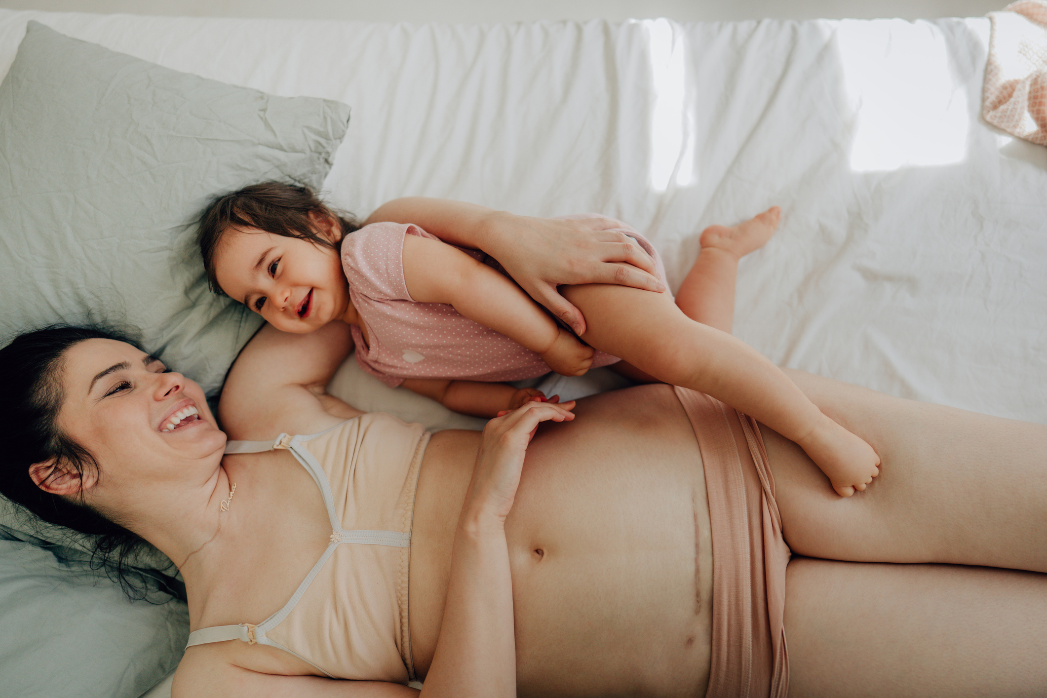 Mother with c-section scar and her baby lying on the bed