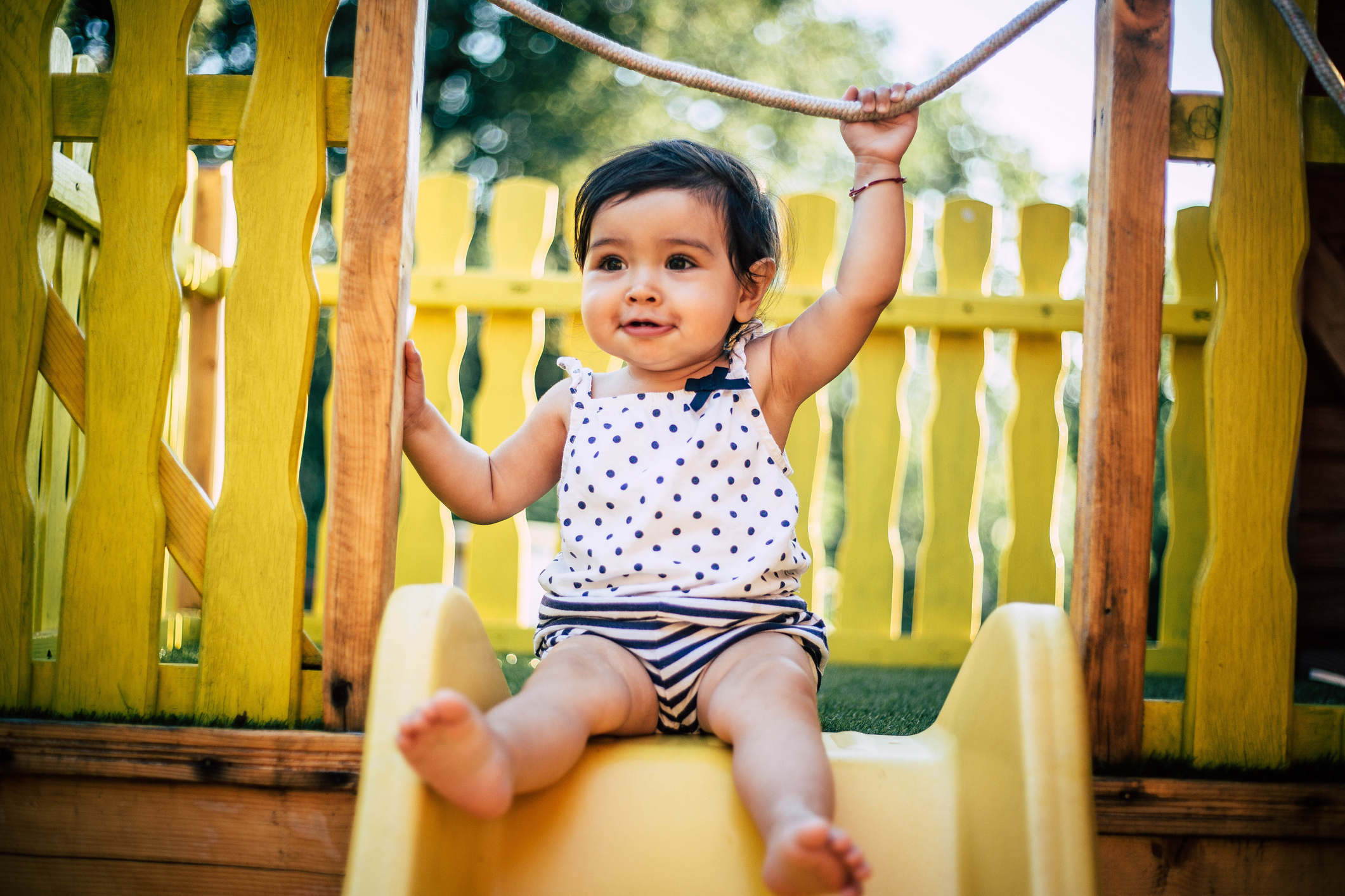 A baby girl plays outside on a play set on a nice day