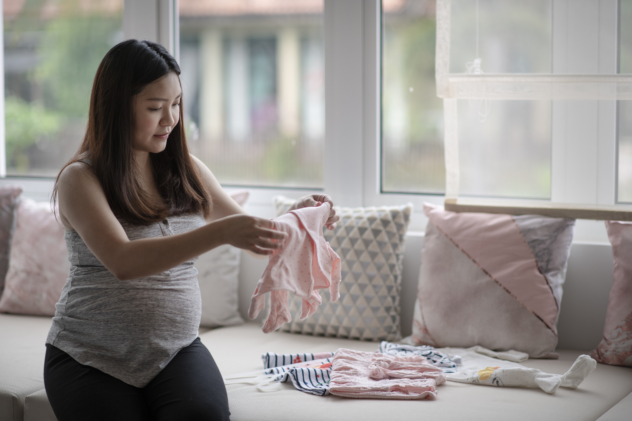Pregnant woman prepares a nursery by folding baby clothes