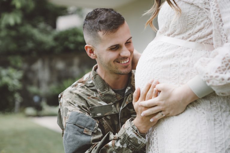 Smilling soldier smiles at his wife's baby bump