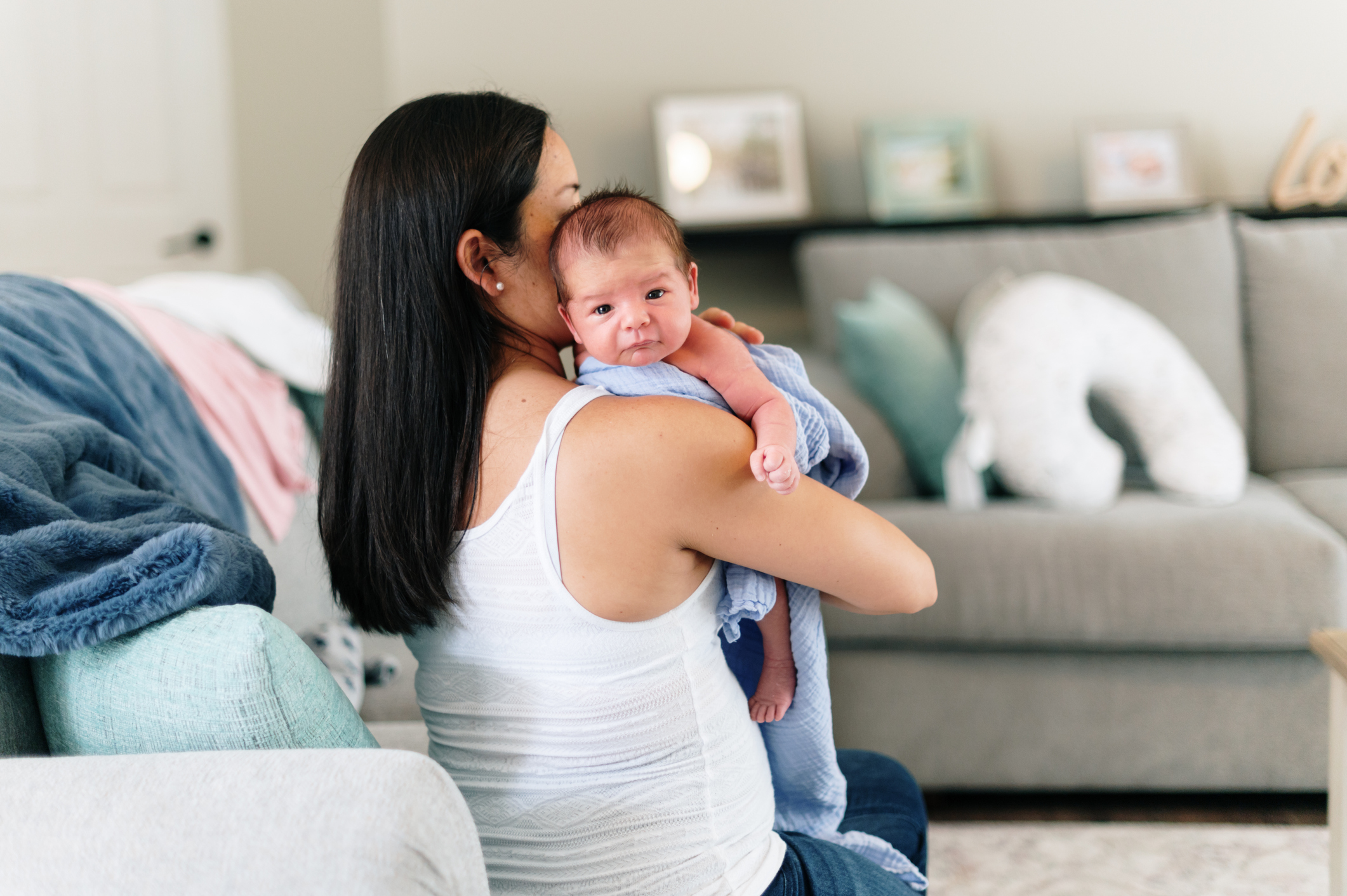 Latina mother holds newborn baby over her shoulder to burp them