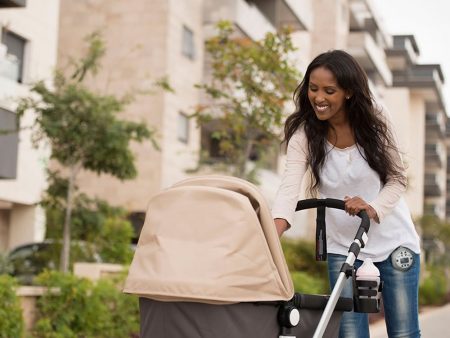 A woman smiles at her baby in a stroller while on a walk
