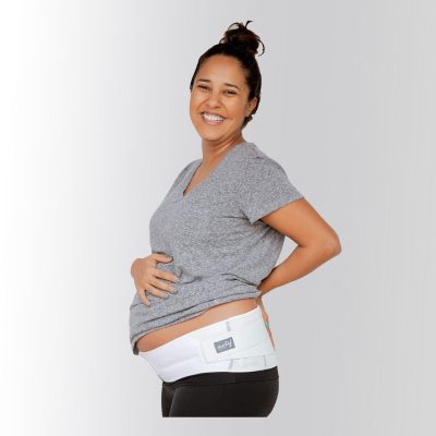 A pregnant woman smiles and wears pregnancy support bands