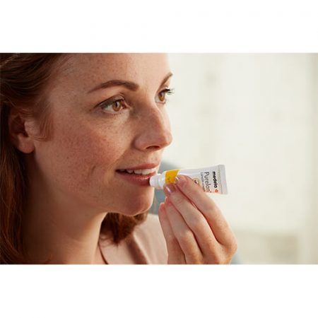 A woman applies Purelan Lanolin cream on her lips