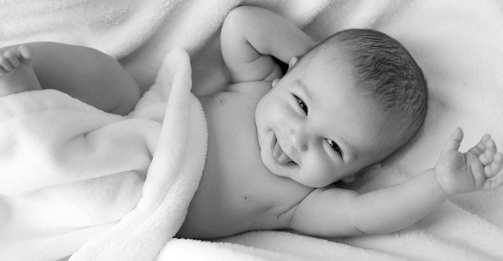 A black and white photo of a smiling baby in a blanket