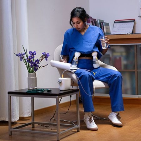 A woman in scrubs works and pumps with the Medela Pump In Style breast pump