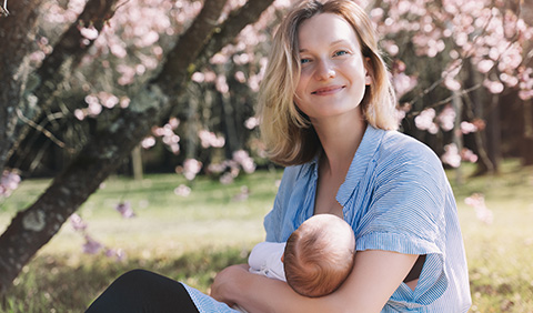 A young mom holds her newborn outside