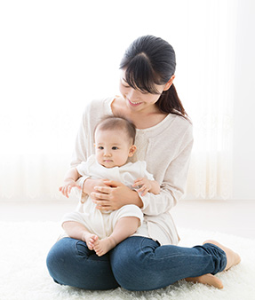 A mom sits on the floor with her baby in her lap