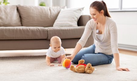 Mother plays with child while wearing Momcozy S12 Breast pump