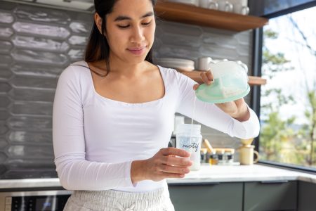 Image showing a mom in her kitchen pouring milk from a Motif Aura Glow into a bottle